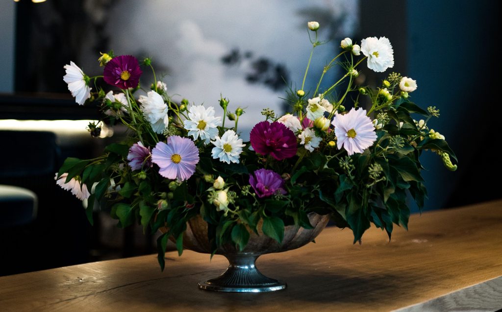 Blumenarrangement vor dunkelblauer Wand